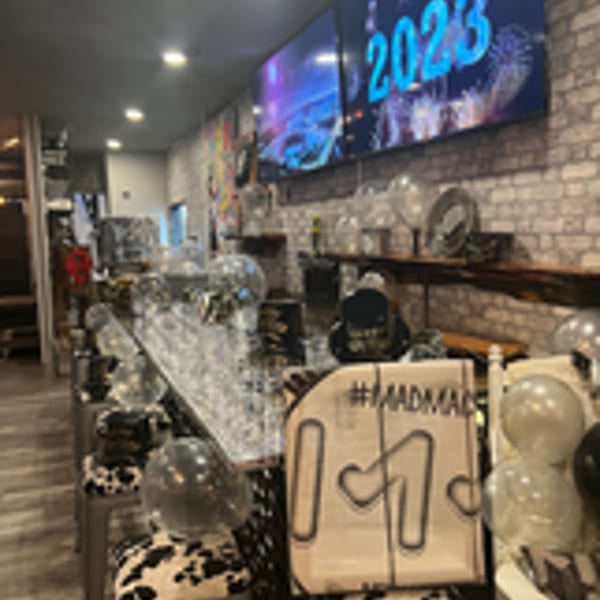 MadMacs restaurant interior decorated for New Year's Eve with balloons, party hats, and a "2023" screen.