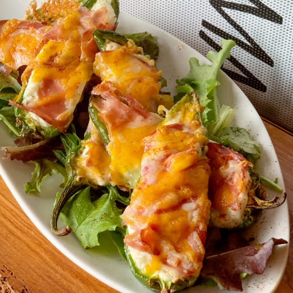 MadMacs jalapeño poppers, stuffed with cheese and wrapped in bacon, served on a bed of greens.